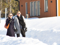 Pariskunta lumisella tiellä, taustalla talo. Kuva Ilona Leikas