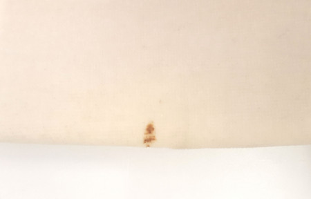 Valkoisen messukasukan pääntien pintalikaa ja helman viinitahra ennen pesua. Kuva Suomen käsityön museo (SKM) (Craftmuseum.fi)